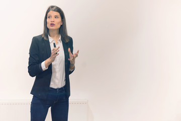 Pretty young businesswoman, teacher or mentor coach speaking to young students in audience at...