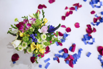 Small beautiful bouquet with different flowers and an Orchid on the table, strewn with petals and confetti