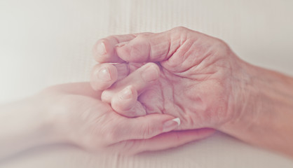 Helping hand. The hand of a young woman carefully supports the wrinkled hand of an old woman