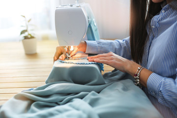 woman sews on sewing machine in real room