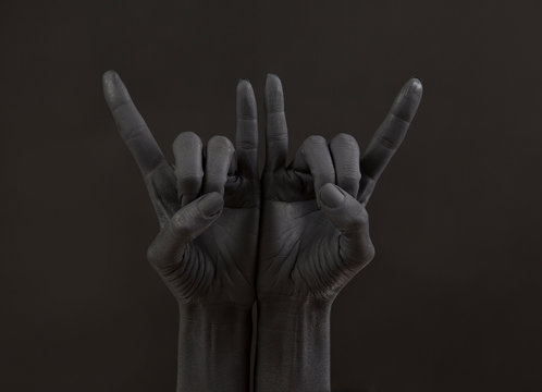 Goat gesture on a dark background. Black hand doing rock symbol. Hands up at a rock concert.