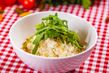 Risotto with gorgonzola, walnuts and arugula on white plate. Close up