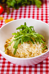 Risotto with gorgonzola, walnuts and arugula on white plate. Close up