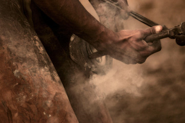 Blacksmith working on a hoof and putting a horseshoe on