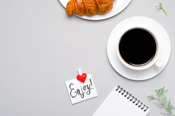 Freshly Baked Croissant, Cup of Coffee and Enjoy Note on Grey Background