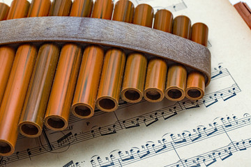 Close up of wooden pan pipes on a piece of classical sheet music