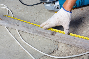 The worker measures the distance with the ruler on wooden
