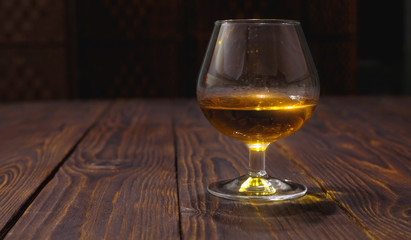 Glass of whiskey or brandy on wooden table
