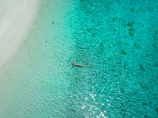 Fototapeta premium TOP DOWN: Relaxed female tourist on vacation resting in the turquoise water.