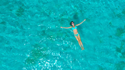 DRONE: Flying away from Caucasian woman swimming on her back by the exotic beach