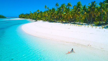 Fototapeta na wymiar DRONE: Tourist girl in bikini sunbathing on the beautiful exotic island beach.