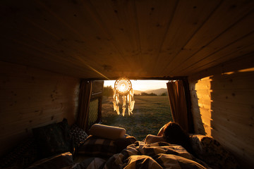 Beautiful view from camper van during sunrise in summer with woman in a bed