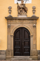 Old door of a historical building with statues and coats of arms made of stone