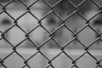 Fototapeta premium Zaun Maschendraht in schwarz weiß mit unscharfem Hintergrund