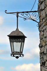 Old lantern on the stone wall of the old castle against the background of the blue sky