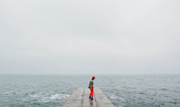 Woman walking on the empty beach in winter time. Art photo with added film and grain filter