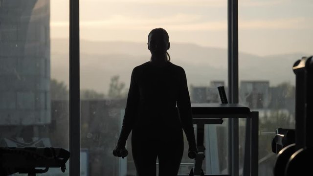 Silhouette of woman middle age doing exercise with dumbbells.
