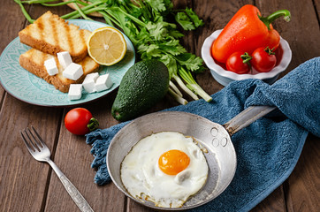 Vegetarian breakfast of fresh vegetables and avocado on a wooden table.