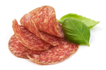 Thinly Sliced Salami with basil leaves, isolated on a white background. Close-up