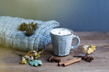 Cozy autumn setting with cup of cofee , book , candle and lights in a wooden tray and a blanket
