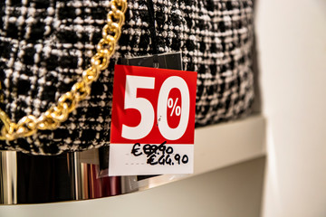 Bag with red price tag and discount in the window of an Italian bags and fashion store during the winter sales of January.