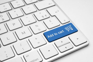 Add to cart blue button with a cart icon on a white isolated keyboard. Online shopping concept.