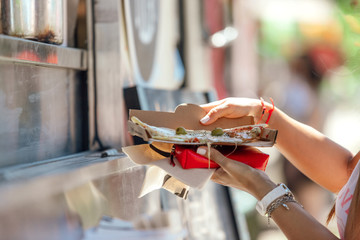 Close-up of woman's hands holding a slice of pizza on a food truck © simonmayer
