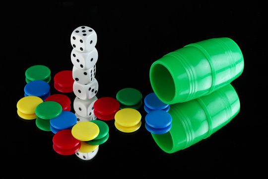 A green shaker, dices and pieces of different colors