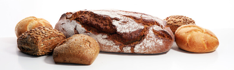 Different kinds of bread and bread rolls on board from above.
