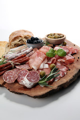 Marble cutting board with prosciutto, bacon, salami and sausages on wooden background. Meat platter