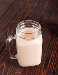Glass cup of hot cocoa with milk on  wooden table.