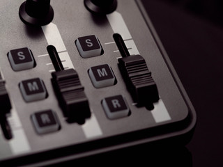 Schiebeschalter, Druckknöpfe und Drehregler an einem Keyboard vor schwarzem Hintergrund