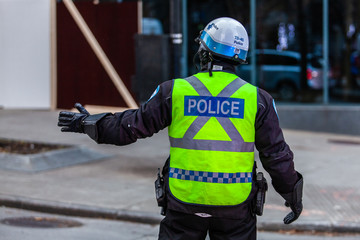 Police ensuring security at a protest. Seen from the back with yellow flashy clothing. Making signs for the traffic