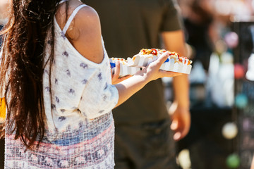 Woman holds two hot dogs at a food fair