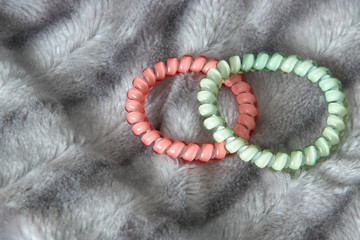Obraz premium Two pink and Light green blue scrunchy hair tie elastic spring on the silver gray fluffy faux fur blanket background