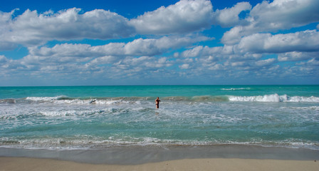 Fototapeta na wymiar Holiday Paradise Deserted beach turquoise sea, blue sky, man beckons to swim
