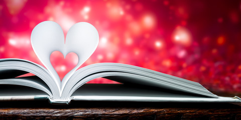 
Book Heart Shape Pages On Wooden Table With  Soft Glowing Romantic Red Background