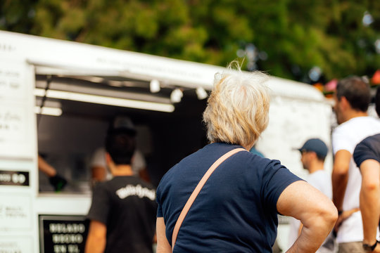 Hoary old woman waits in the row of a food truck