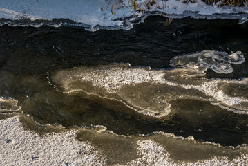 Gefrorener Fluss. Eisscholle. Schöner sonniger Tag in einer Schneelandschaft mit teilweise gefrorenem Fluss