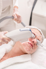 Naklejka premium Anti acne phototherapy with professional equipment. Beautiful woman in beauty salon during photo rejuvenation procedure. Laser face skin treatment at cosmetic clinic. Hardware cosmetology