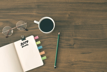 2019 goals list with notebook , cup of coffee over on wooden background.