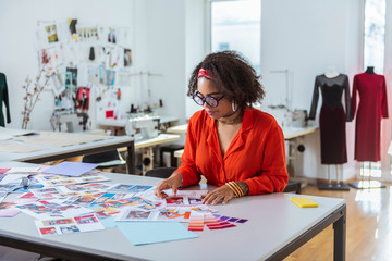 Concentrated young female with short curly hair dealing with sketches