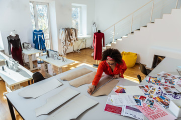 Concentrated curly African American designer using measuring tape