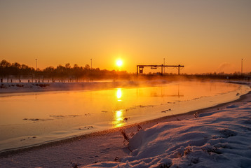 Sonnenuntergang über Fluss in schneelandschaft mit Industrie