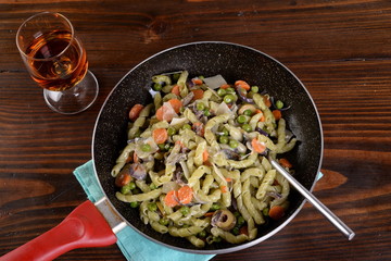 Frying pan with spinach busiate and gorgonzola dressing with peas and carrots  