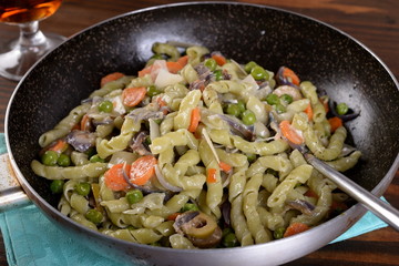 Frying pan with spinach busiate and gorgonzola dressing with peas and carrots  