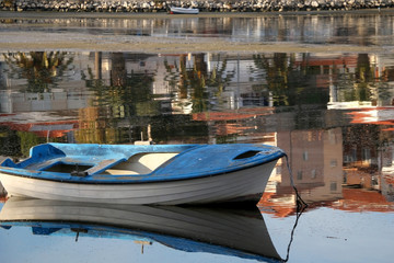 Small old fishing boat in a shallow sea. Colorful reflections in the background. Selective focus.