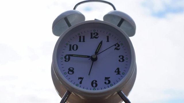 Desktop alarm White clock Timelapse Start time 05.15 Clock walking 25 minute. moving fast on Blue skybackground.