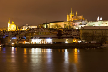 Obraz premium Night snowy Christmas Prague Lesser Town with gothic Castle above River Vltava, Czech republic