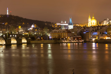 Obraz premium Night romantic snowy Prague St. Nicholas' Cathedral above River Vltava, Czech republic